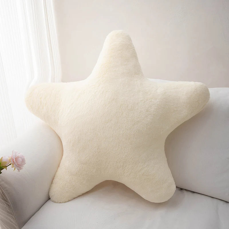 Soft star-shaped plush pillow in pastel color resting on a cozy bed or sofa