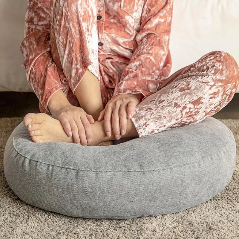 Neutral-colored floor seat cushion placed on a rug in a minimalist room setting