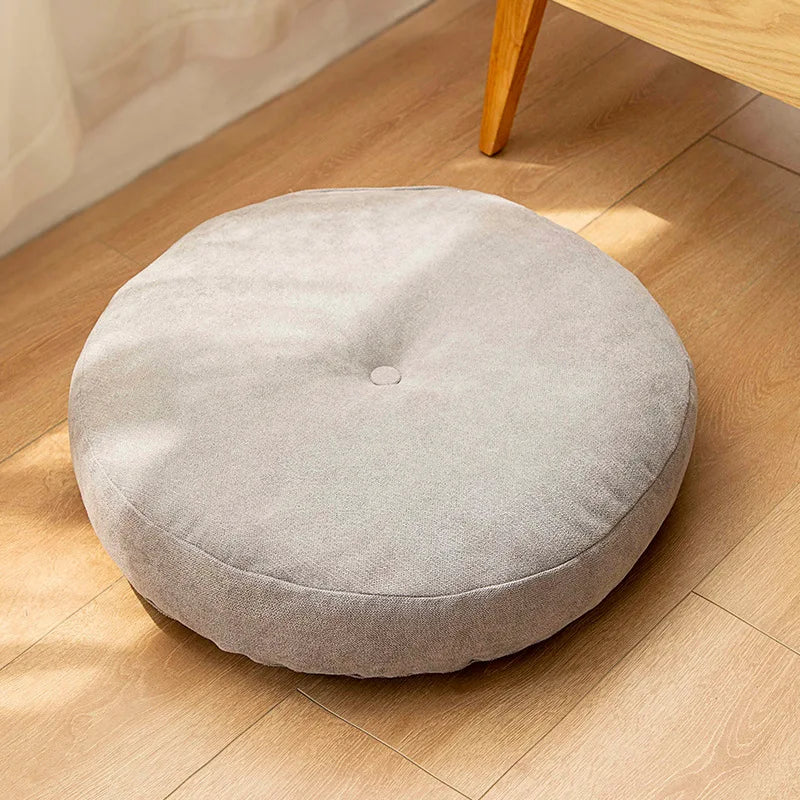 Neutral-colored floor seat cushion placed on a rug in a minimalist room setting