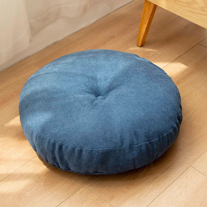 Neutral-colored floor seat cushion placed on a rug in a minimalist room setting