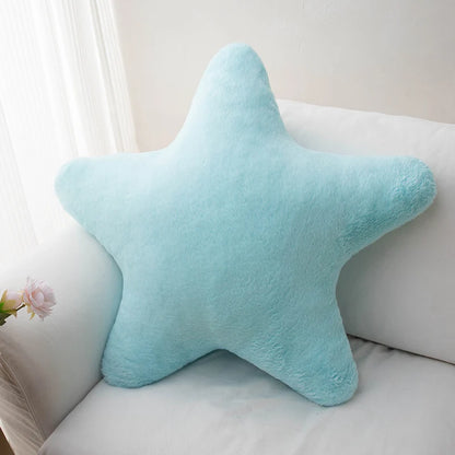 Soft star-shaped plush pillow in pastel color resting on a cozy bed or sofa
