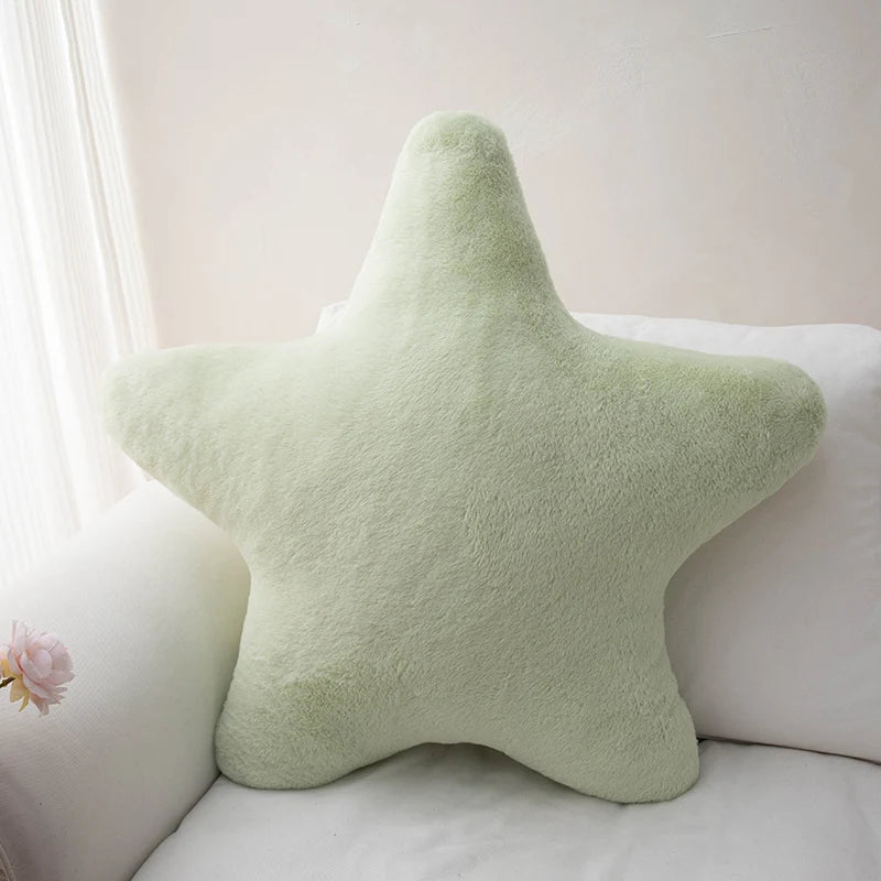 Soft star-shaped plush pillow in pastel color resting on a cozy bed or sofa
