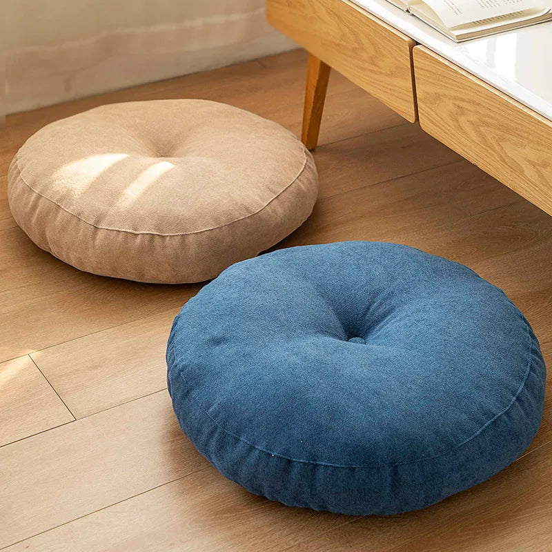 Neutral-colored floor seat cushion placed on a rug in a minimalist room setting

