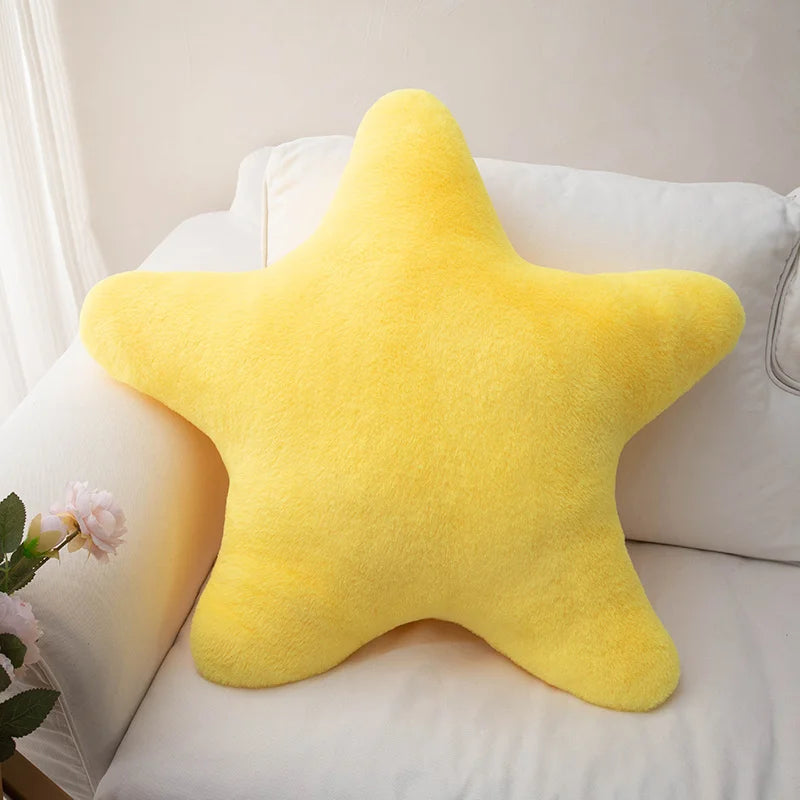 Soft star-shaped plush pillow in pastel color resting on a cozy bed or sofa
