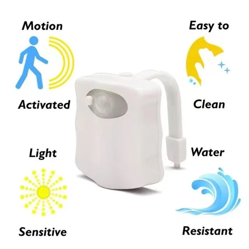 LED toilet night light glowing in soft colors attached to toilet bowl in a dark bathroom

