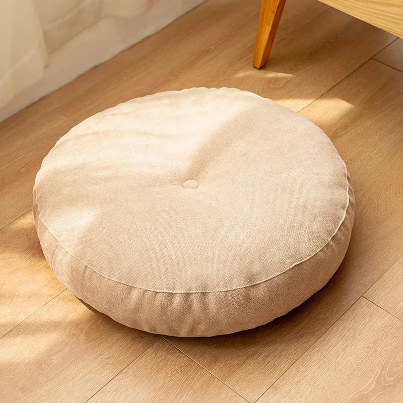 Neutral-colored floor seat cushion placed on a rug in a minimalist room setting
