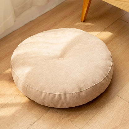 Neutral-colored floor seat cushion placed on a rug in a minimalist room setting

