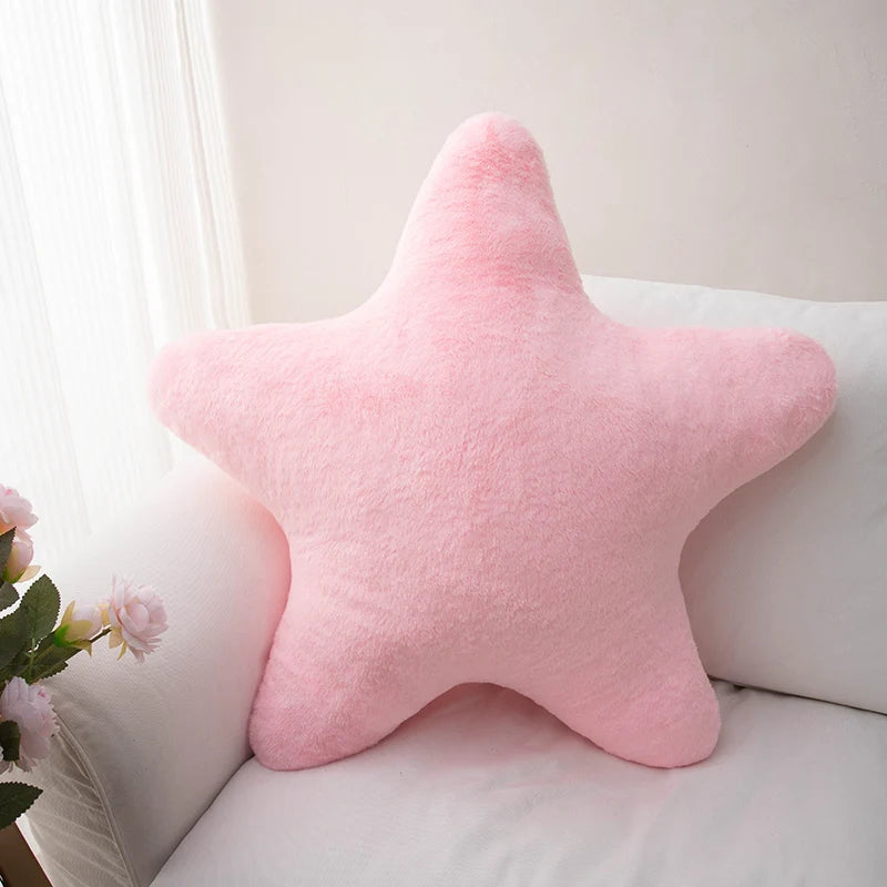 Soft star-shaped plush pillow in pastel color resting on a cozy bed or sofa
